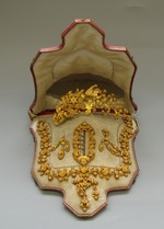 Bronzevergoldete Schmuckgarnitur mit Dekor aus Blüten und Früchten: Halskette, Vorsteckbrosche, Ohrringe, Kamm, Ansteckblume, Gürtelschnalle