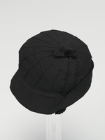 Schwarzer Damenhut, kleine helmförmige Kappe, vollständig 4cm Ripsband, mit rückwärtig aufgeschlagener Krempe, links Zierband mit kleiner Schleife aus gleichem Material am oberen Kopfteil